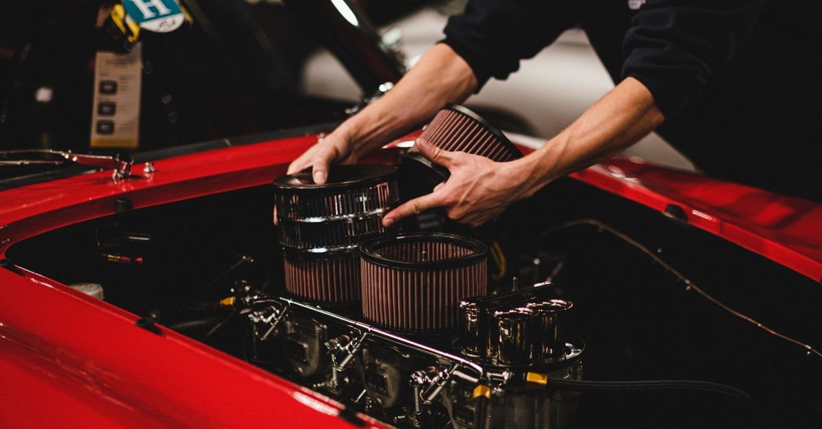 A mechanic fitting an air filter element to an engine, the first item on the manufacturer's own list of causes for a rich-running engine
