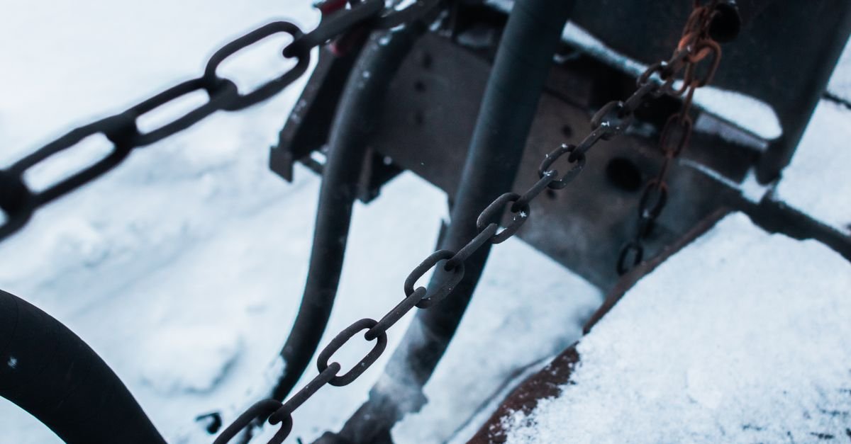 Metal chains and equipment thickly covered in snow, the state a machine comes out of an unheated shed in