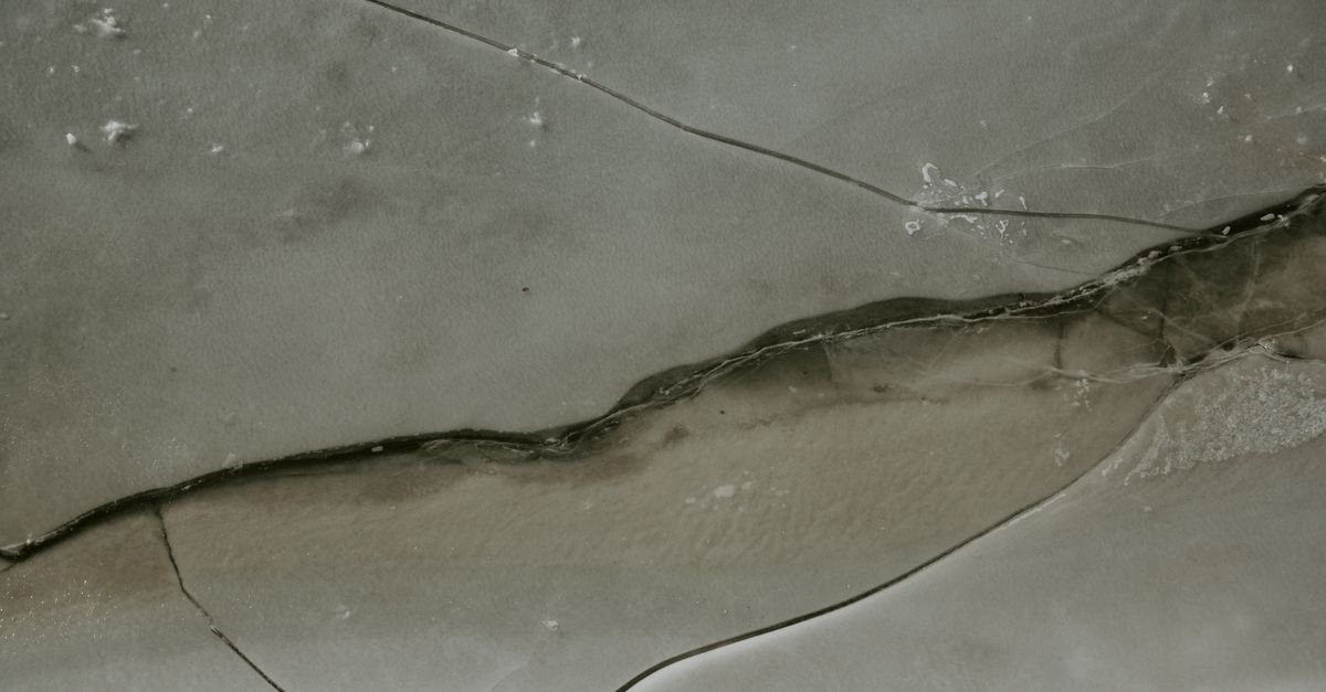 Broken ice surface with snow and cracks running across it, the way a sealed cavity gives up when water freezes inside it