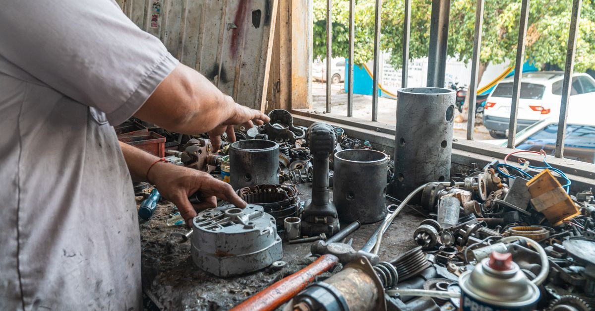 Mechanic laying small components out in order on a workshop bench before a rebuild