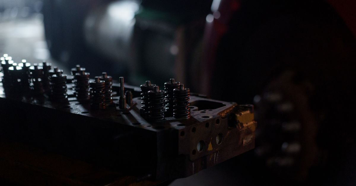 Valve springs on an engine cylinder head in a dim garage, the assembly whose clearance quietly closes up over years of running