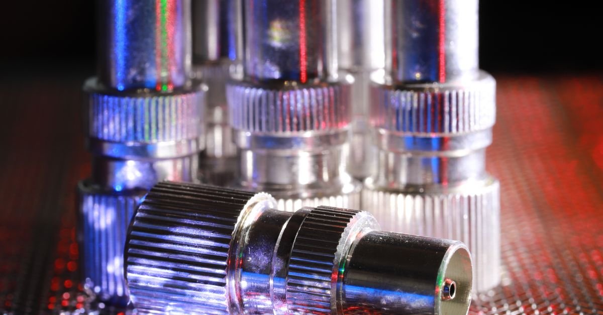 Close-up of machined metal hose connectors under dramatic lighting, the crimped end where high-pressure hoses most often fail