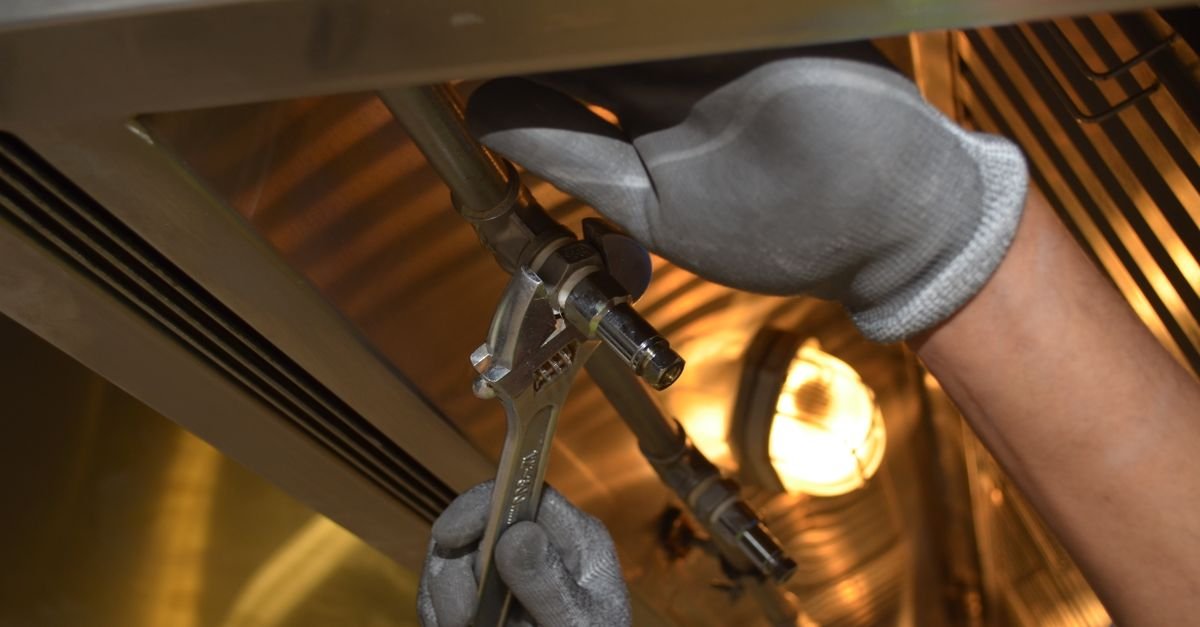 A worker separating a pipe fitting with hand tools to reach the seal inside