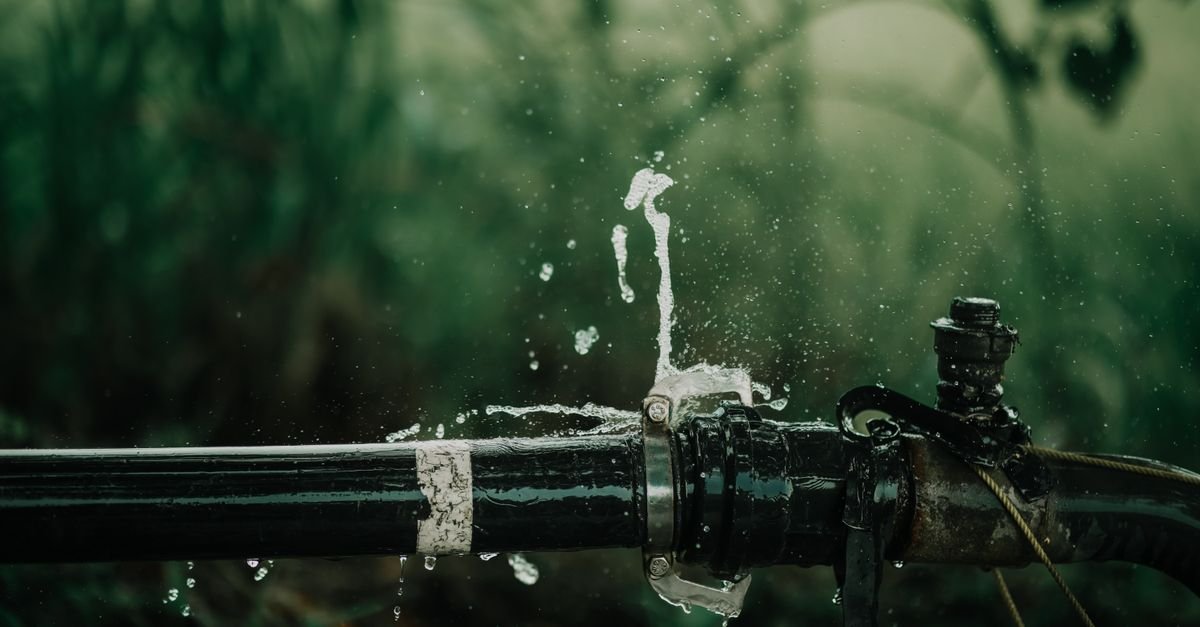 Water escaping from a pipe joint outdoors, the same pattern a leaking O-ring makes at a hose fitting