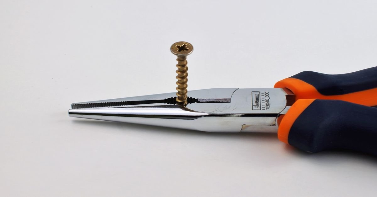 Long-nose pliers gripping a small metal component, the tool needed to lift a pressure washer inlet filter screen out of its fitting