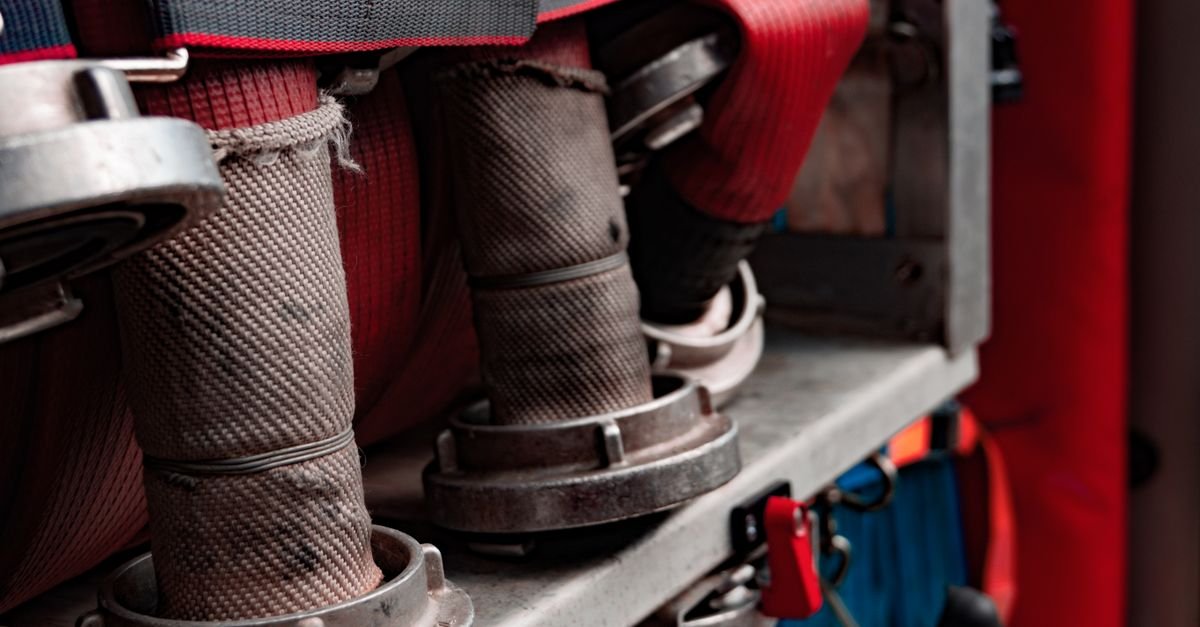 Coiled fire hose showing the woven textile jacket that carries the load in a reinforced hose wall