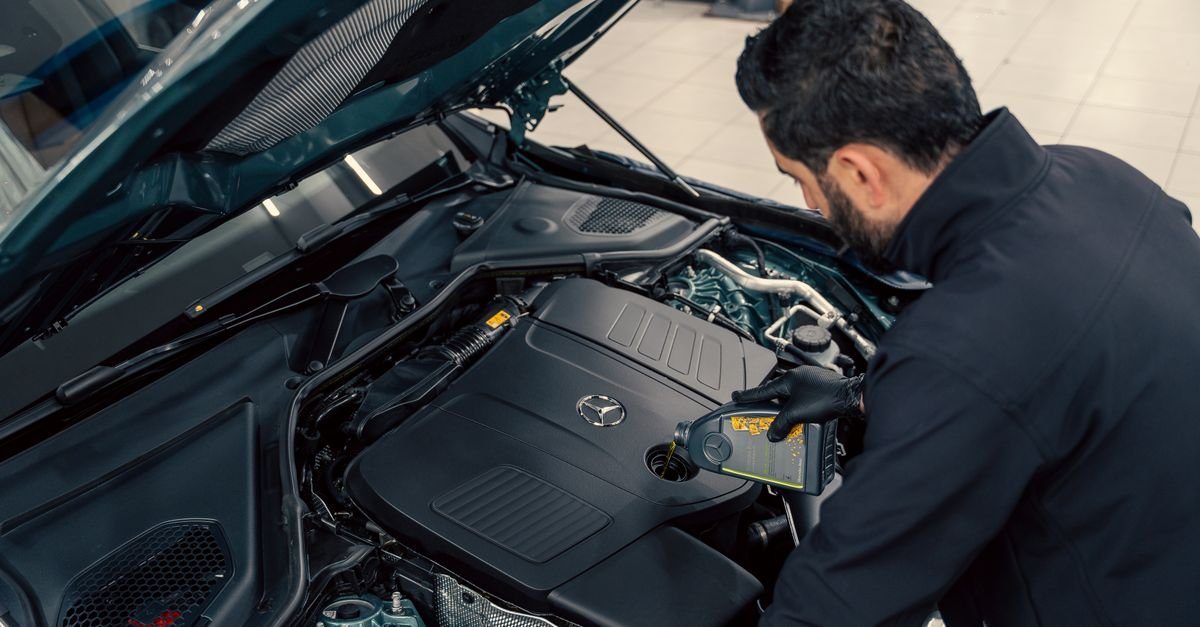 A technician filling oil into an engine through the fill point during a service