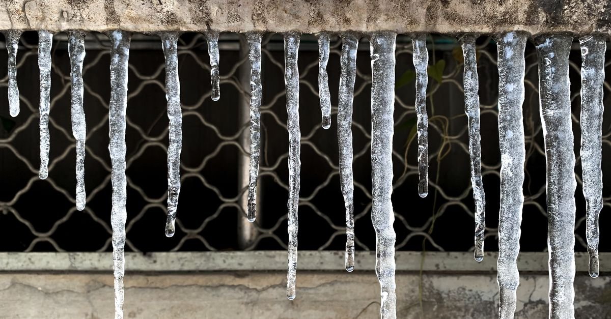Clear icicles hanging from a metal bar in freezing conditions