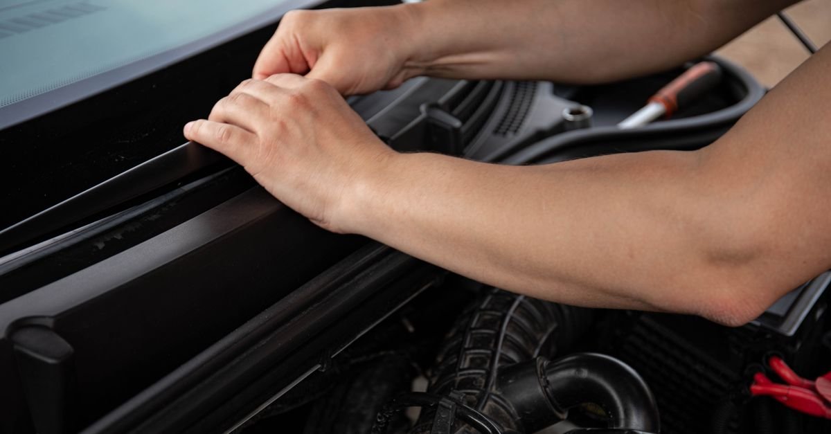 Close-up of a mechanic's hands working on an engine assembly with the components exposed
