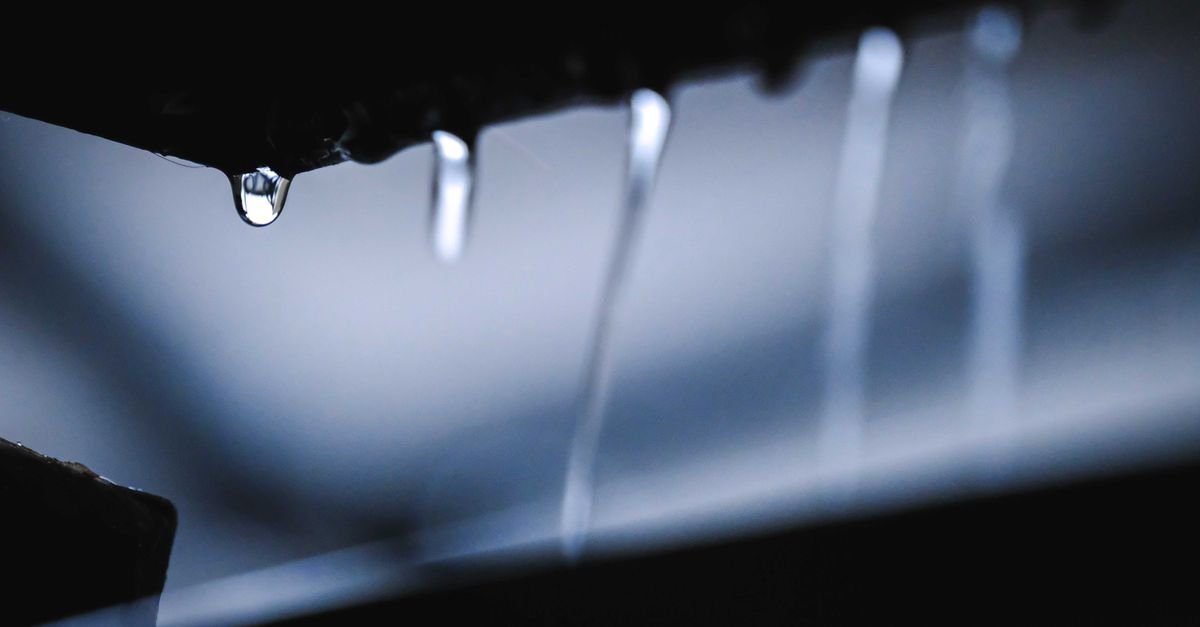 Water running in fine streams down a dark vertical surface