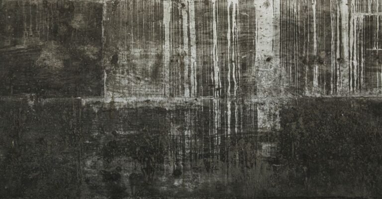 A concrete surface marked with darker vertical streaks and uneven tonal bands