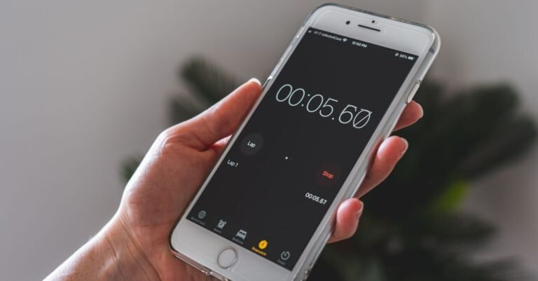 A hand holding a smartphone with the stopwatch app running, the only tool needed to time how long a pressure washer holds full pressure
