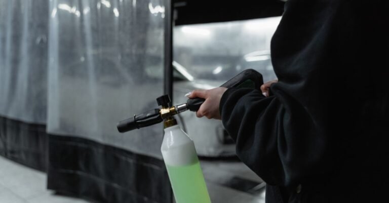Close-up of a spray gun and nozzle assembly held in a garage cleaning bay
