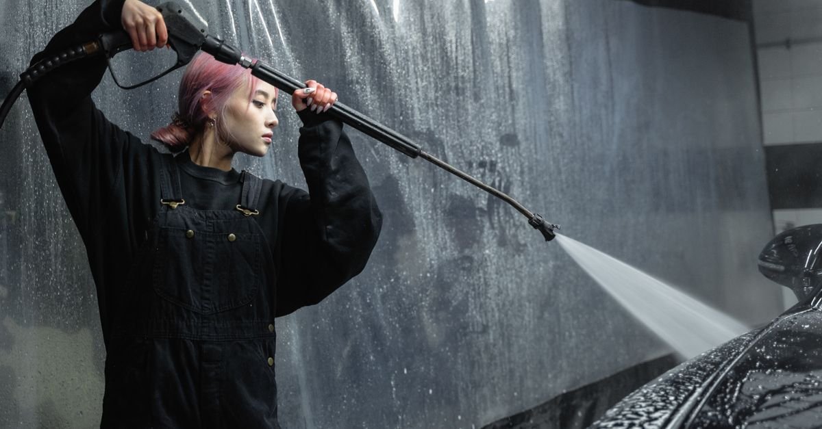 A person holding a pressure washer trigger gun in a garage, the first thing to squeeze before switching the machine on