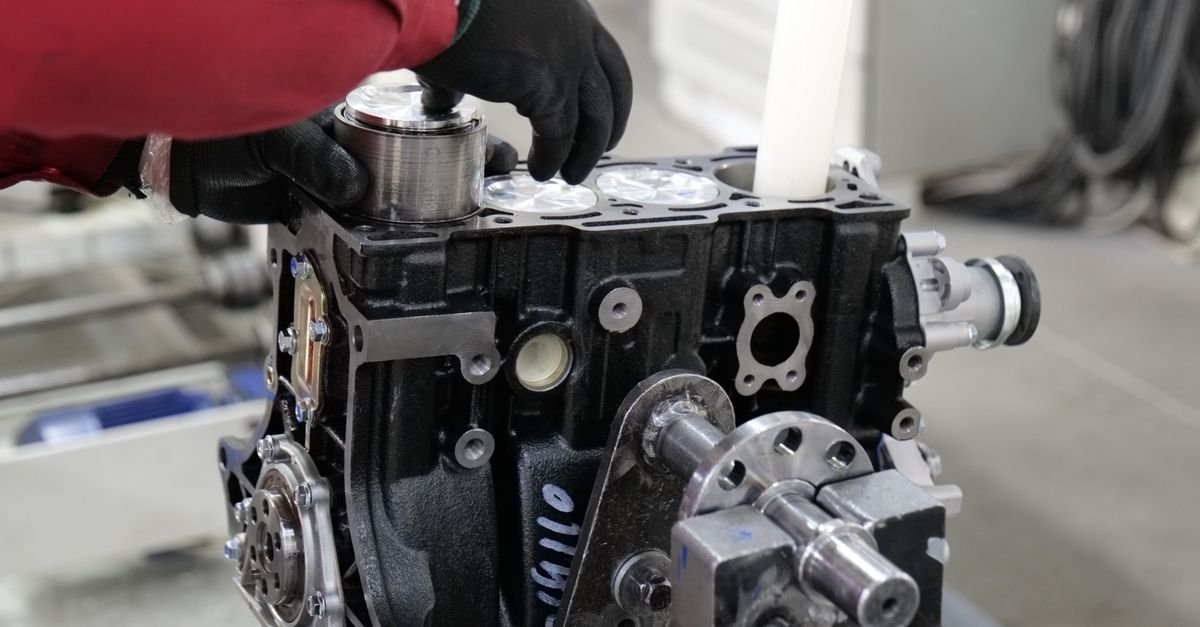 A mechanic working on an engine assembly in a workshop, the stage at which a shaft key is seated before a pump goes on