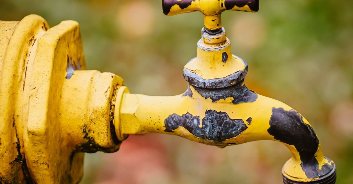 A worn outdoor faucet shot in close focus, the supply point where a replacement pump first tests the flow it was rated for