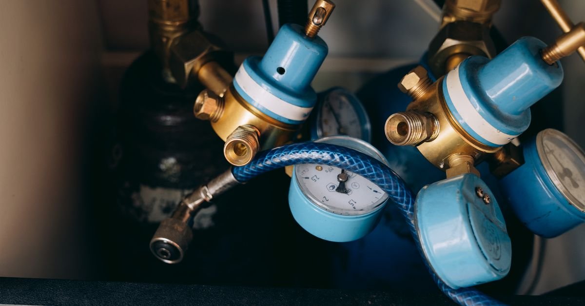 Brass and blue pressure regulators with gauges and tubing, the same family of spring-loaded valve that sets a pressure washer's bypass point