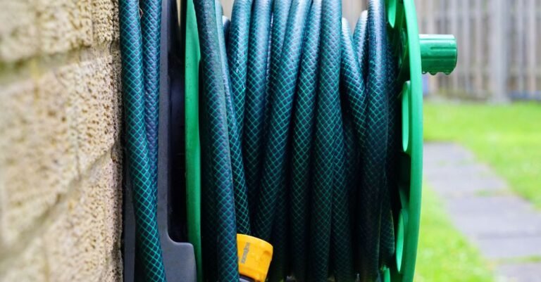 Garden hose neatly coiled on a wall-mounted reel, the supply line to check when a pressure washer has no water coming out