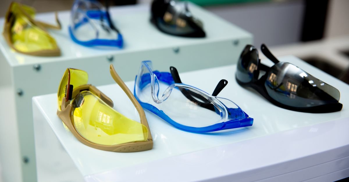 Row of impact-rated protective eyewear with yellow, blue and clear lenses on a display