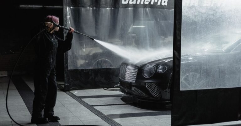 Pressure washer wand producing a wide fan spray pattern while cleaning a car