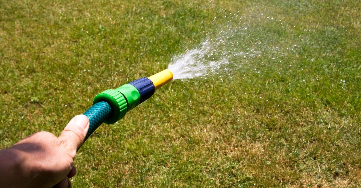 A garden hose running water across grass, the flow that has to match a pump's rated GPM before anything inside the machine matters
