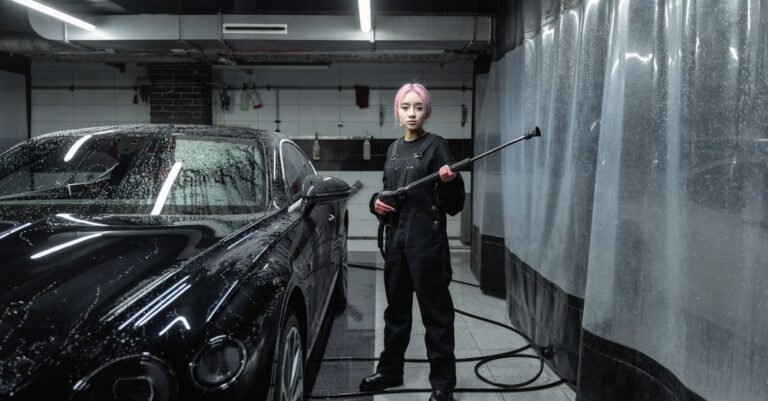 A person gripping a pressure washer lance two-handed while rinsing a dark car, the grip a juddering jet forces you into