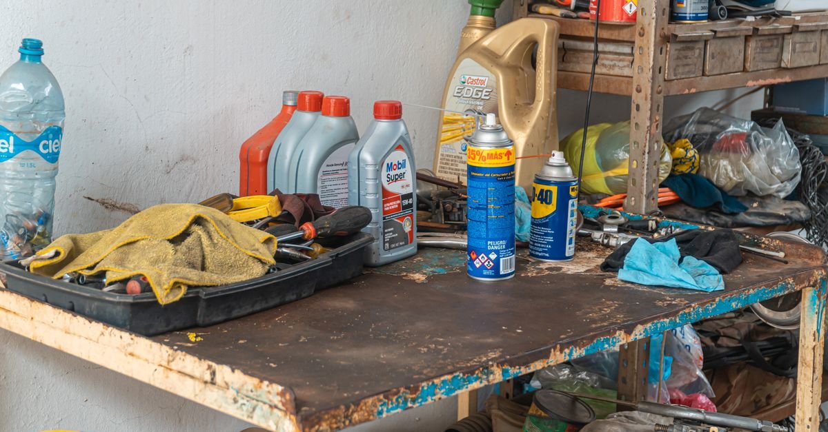 A workbench in a garage with tools, oil cans and maintenance products