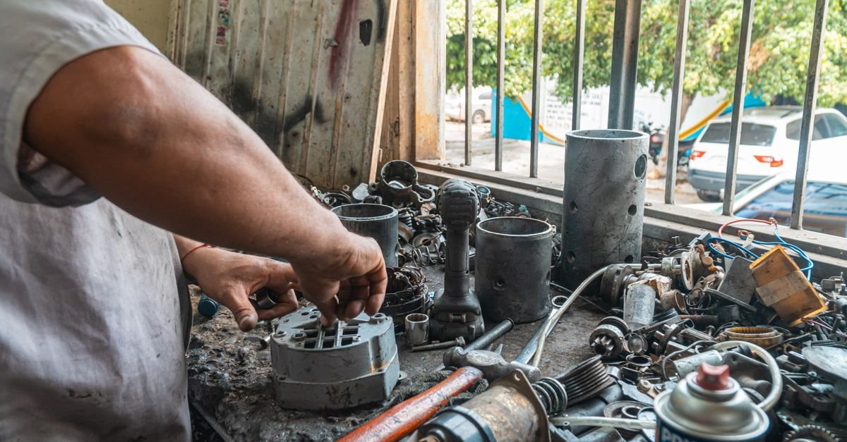 Mechanic's hands examining machine parts laid out on a workshop bench to check a stamped model number
