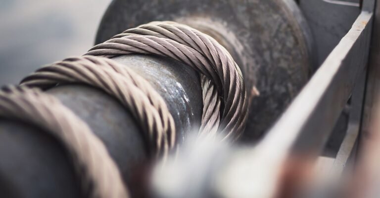 A steel cable wound tightly around a mechanical reel, the same rope-on-a-drum arrangement that sits inside every recoil starter