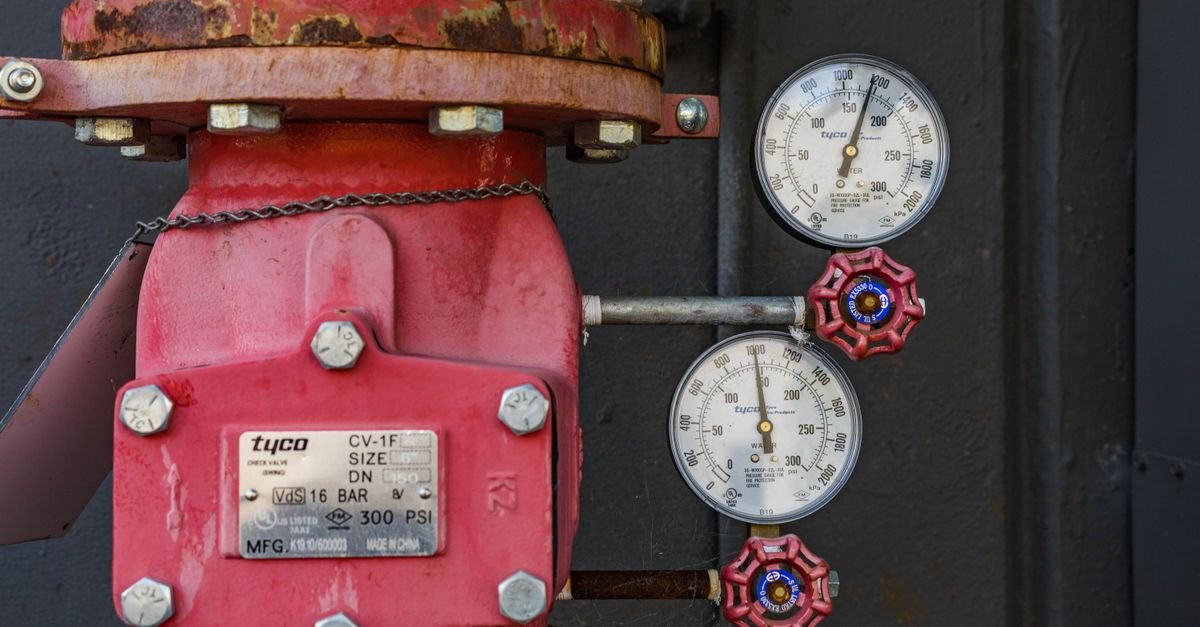 An industrial pressure gauge mounted beside a rusted valve body
