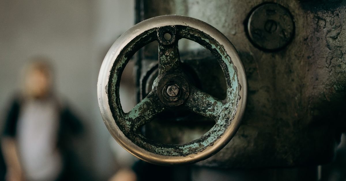 A weathered metal valve photographed close up in an industrial setting