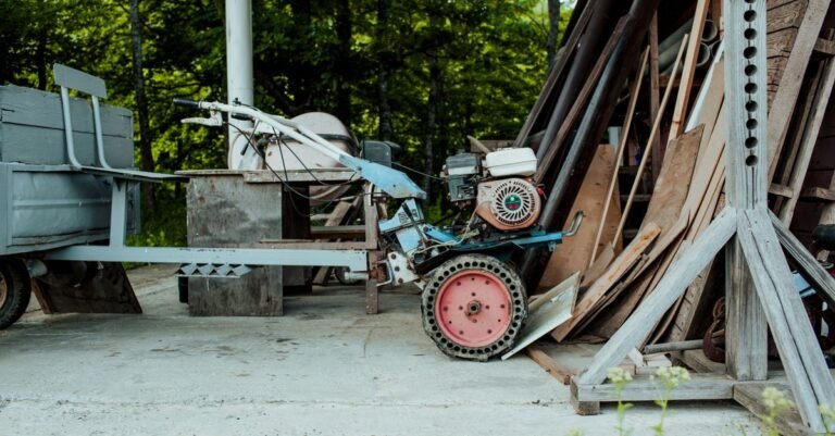 A small single-cylinder gasoline engine bolted to a wheeled cart in a shed, the engine-on-a-frame layout a gas pressure washer uses