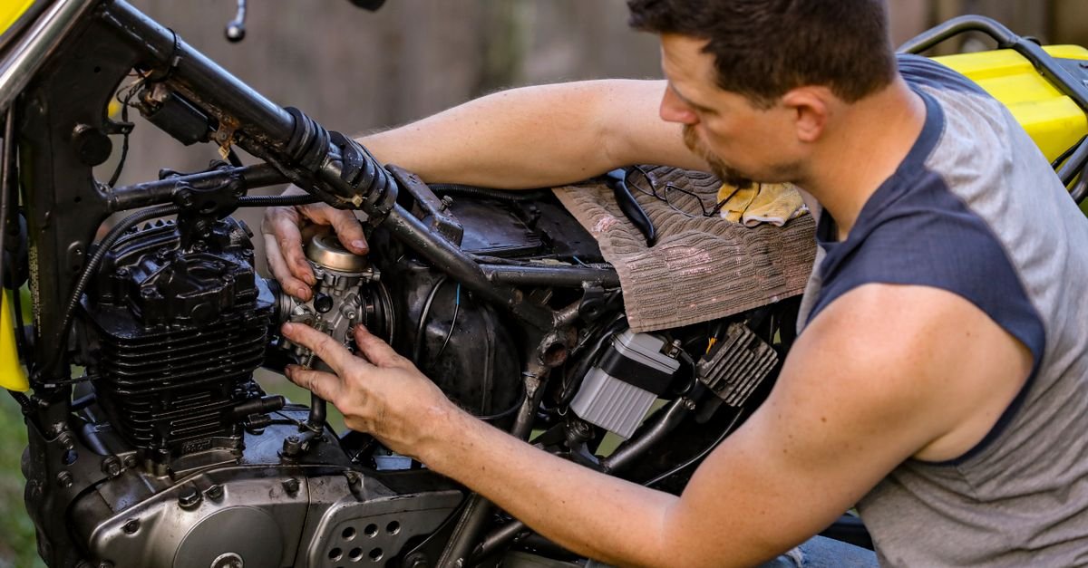 A mechanic working on a small engine carburettor outdoors