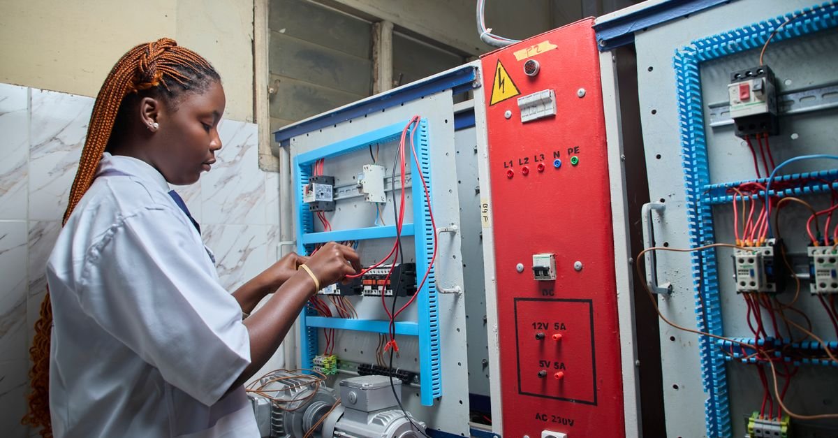A technician working on an electrical control panel in a workshop
