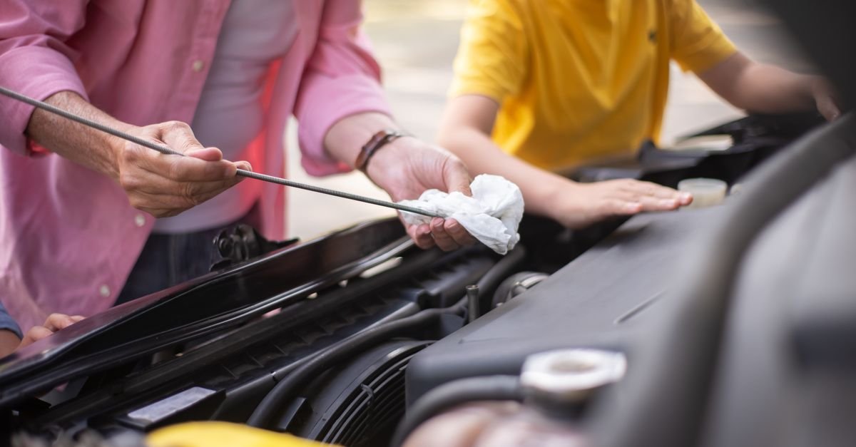 A person checking the engine oil level on a dipstick outdoors
