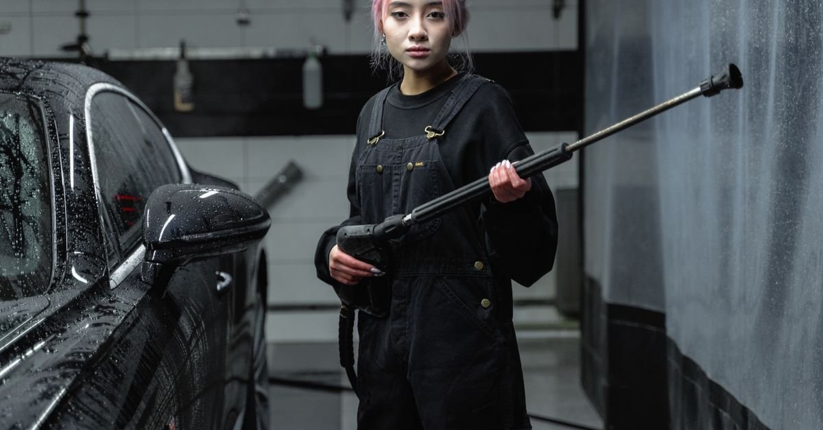 Person holding a pressure washer wand and quick-connect nozzle at a car wash bay