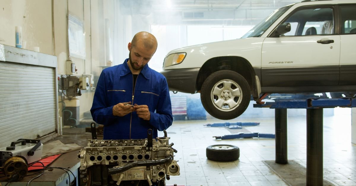 A mechanic in blue overalls inspecting an engine in a professional repair workshop