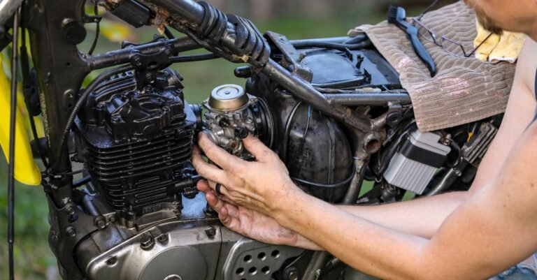 Mechanic working on a small engine carburetor outdoors with hand tools