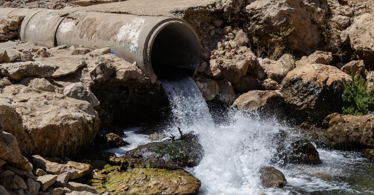 Water discharging at high volume through a large open pipe onto rock