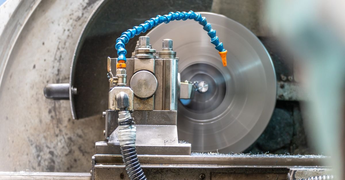 Metal workpiece spinning in a lathe chuck while a tool bears against its surface