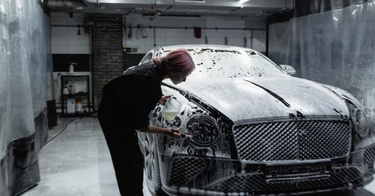 A worker rinsing foam from a car with a pressure washer trigger gun, the moment a total stop system responds to