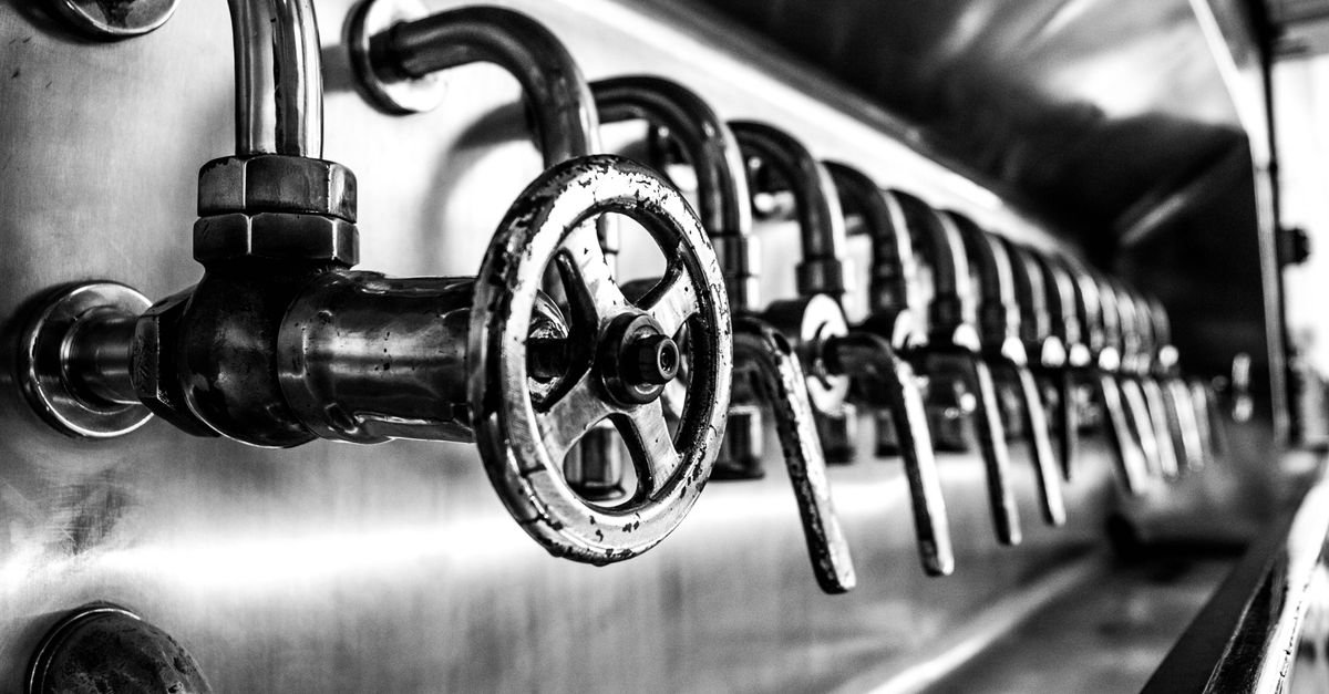 Close-up of industrial valve bodies in monochrome, the kind of spring-and-seat assembly that decides where water goes when a trigger closes