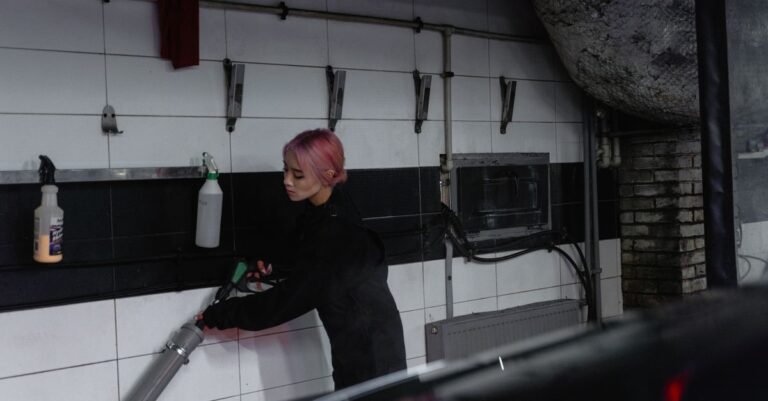 Person gripping a pressure washer trigger gun one-handed while rinsing a car down in a garage