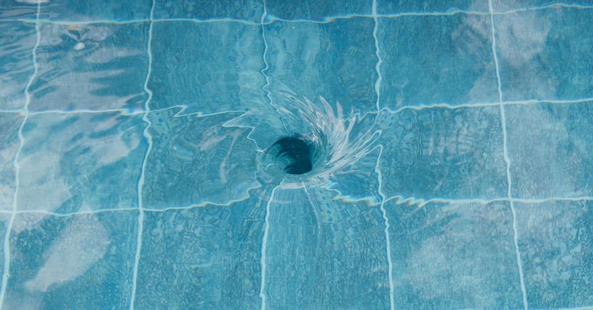 Water spinning in a tight vortex above the drain of a clear tiled pool