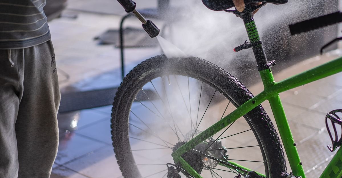 A hose jet playing across a bicycle frame, the kind of dry-surface test that makes the shape of a spray pattern obvious