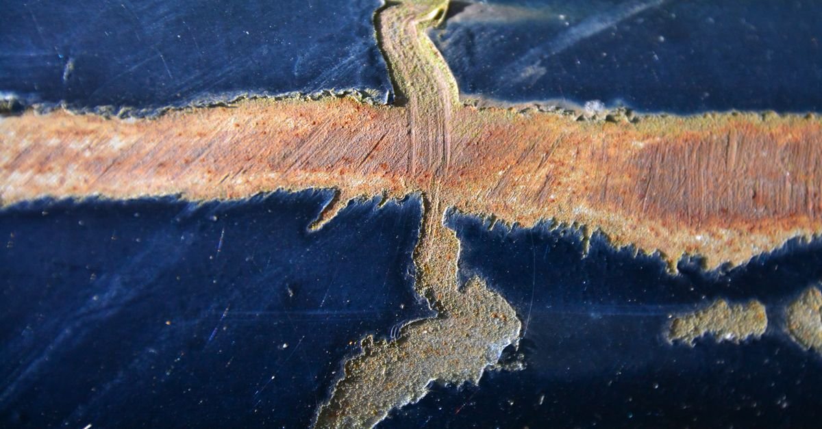 Rusted and decayed metal surface with deep pitting across the face, the pattern corrosion leaves before it goes through