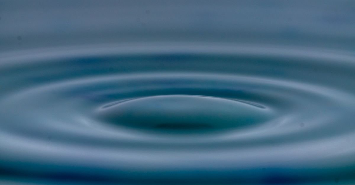 Concentric ripples spreading outward across a still water surface, the same way a pressure wave travels back along a pressure washer hose
