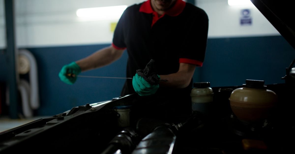 A mechanic examining the oil level on a dipstick in a garage, the first check when pump oil looks wrong