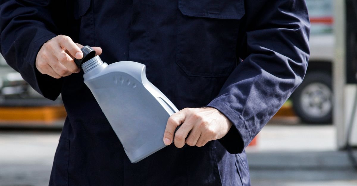 A technician holding a container of oil in working clothes, the one purchase this diagnosis needs