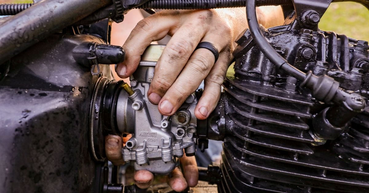 Close-up of hands working on a small single-cylinder engine with hand tools